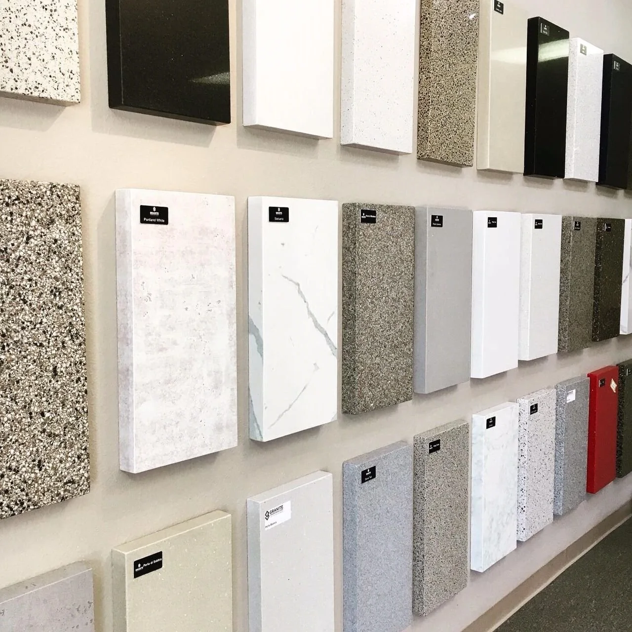 Countertop samples displayed in rows, including solid and veined designs