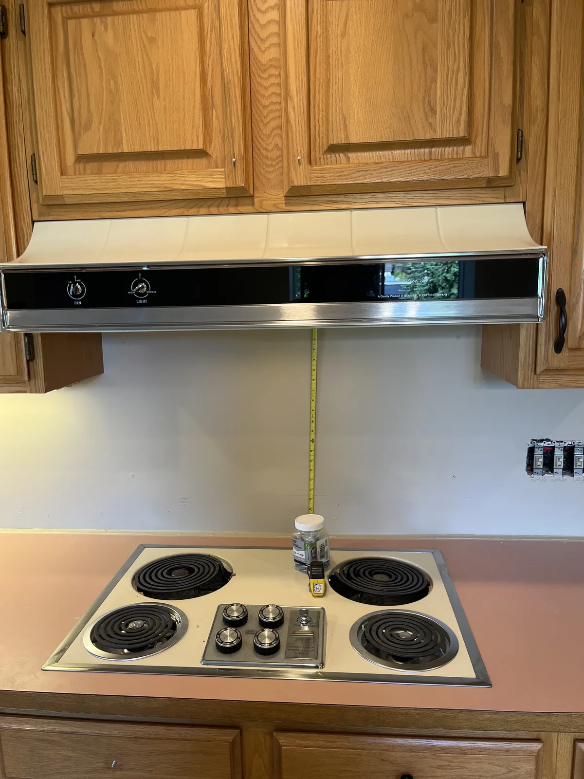 Kitchen before the countertop replacement, with original oak cabinets and dated laminate at the cooktop