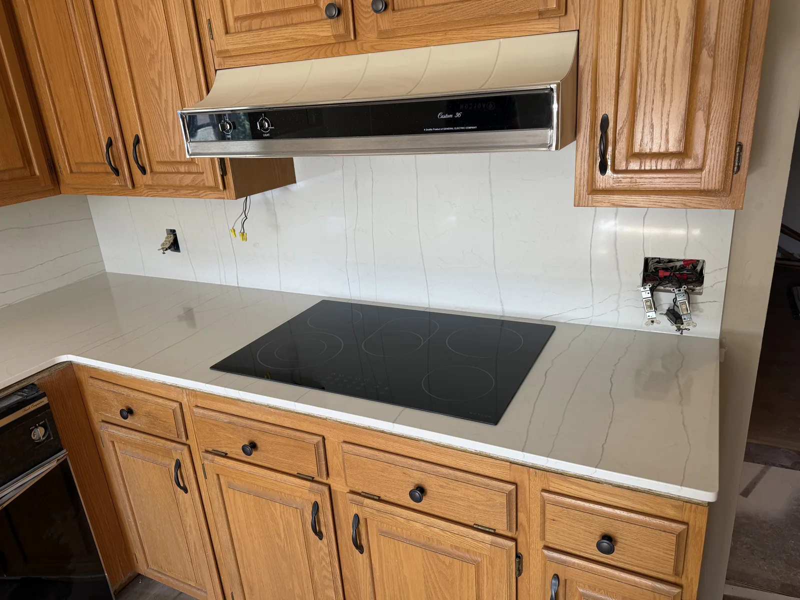 The same kitchen wall after installation, with white veined quartz countertop and a full height quartz backsplash