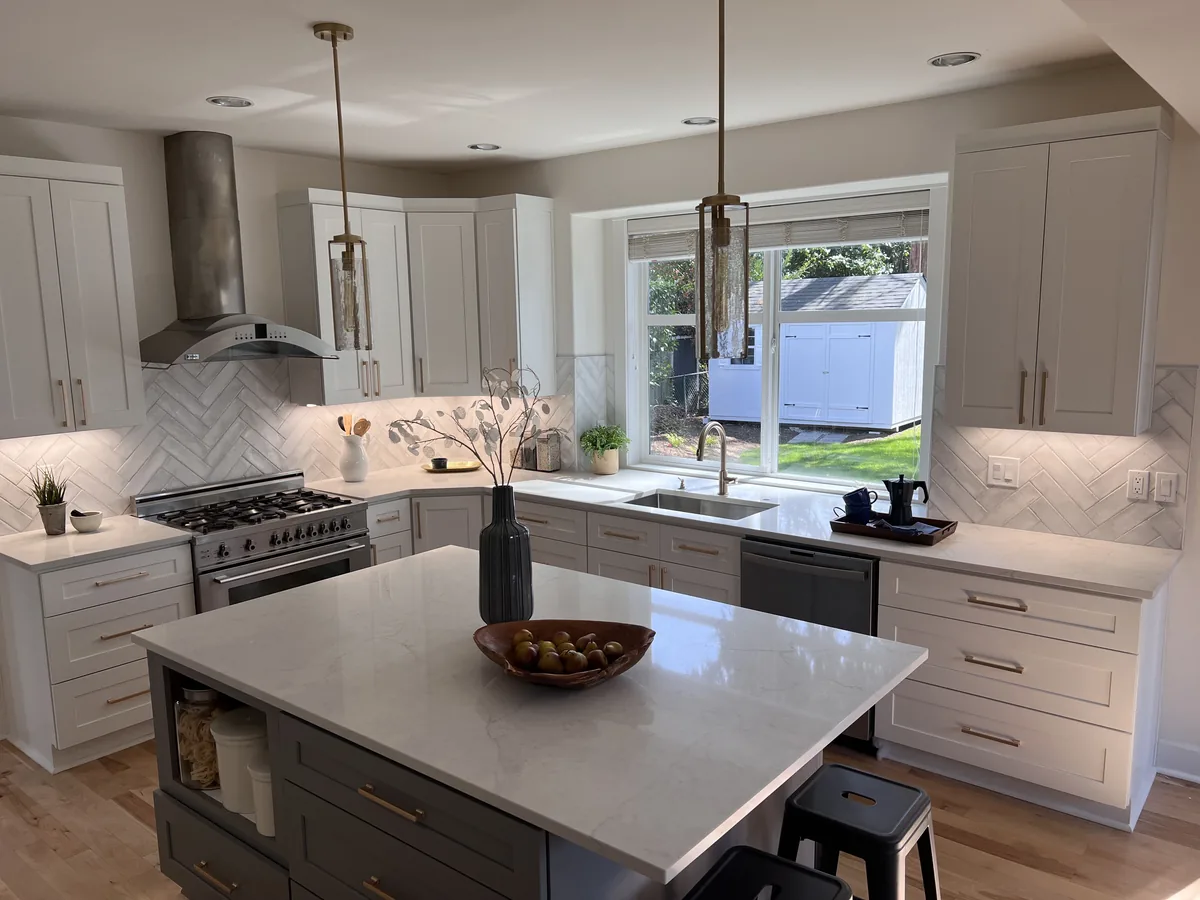 Open kitchen with white cabinets, a dark island base and white quartz countertops on the island and perimeter