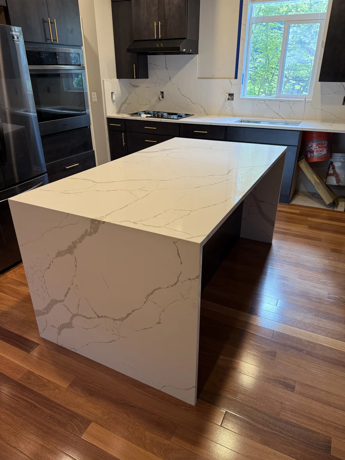 Kitchen island in white veined quartz with a waterfall end panel and a matching full height backsplash