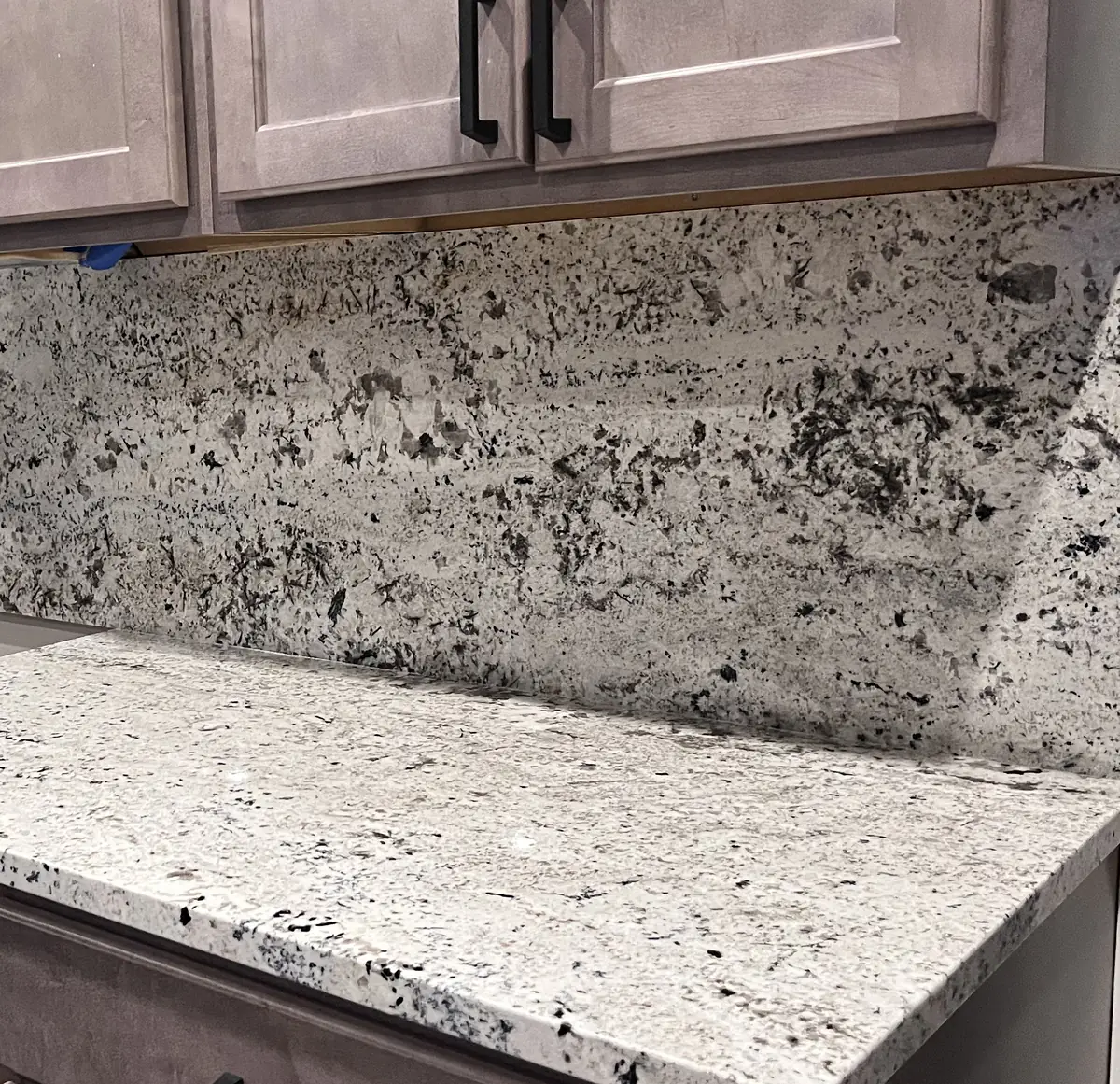 Full height granite backsplash meeting a granite countertop at an inside corner