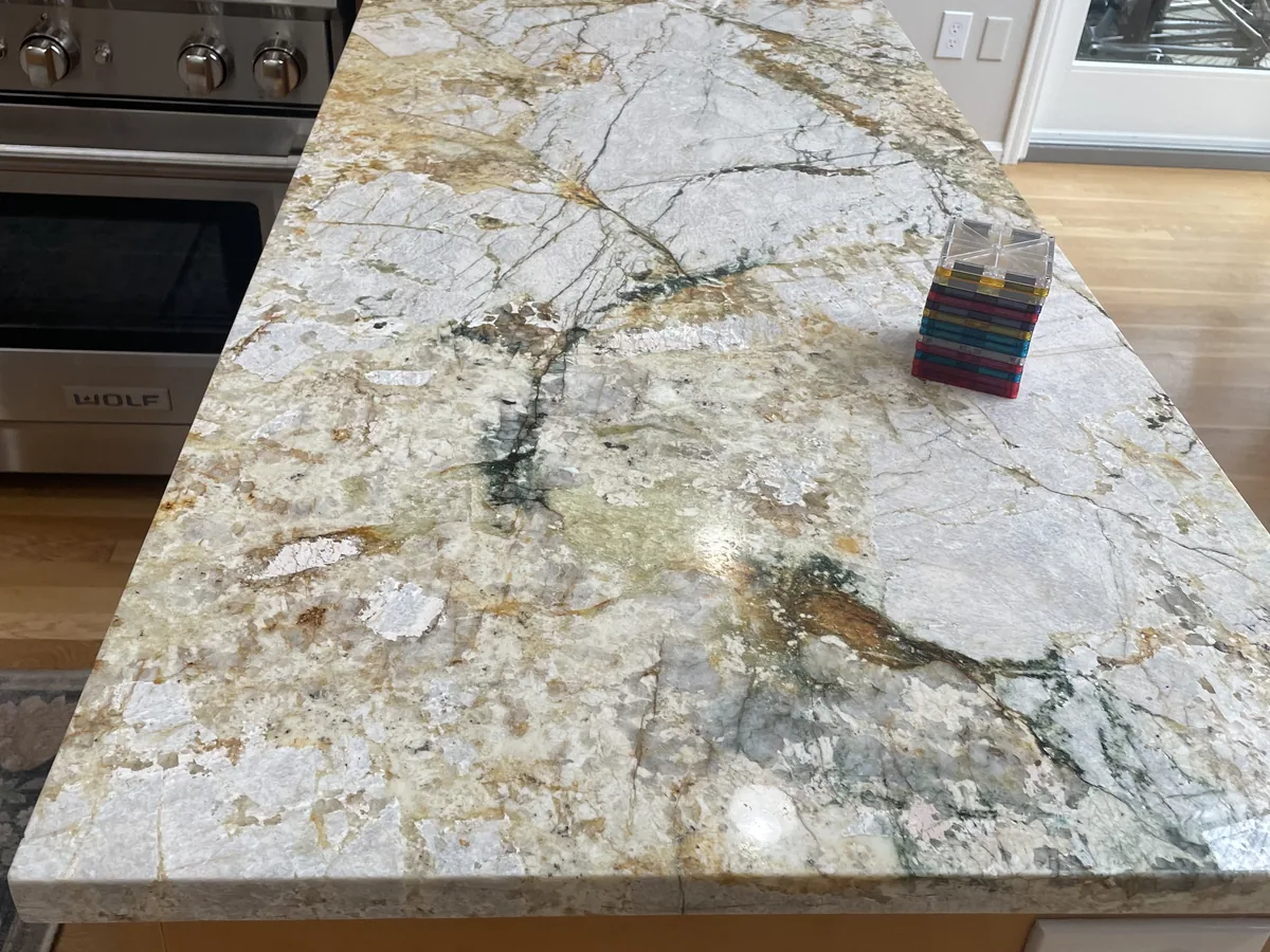 Heavily veined natural stone island countertop beside a professional stainless range