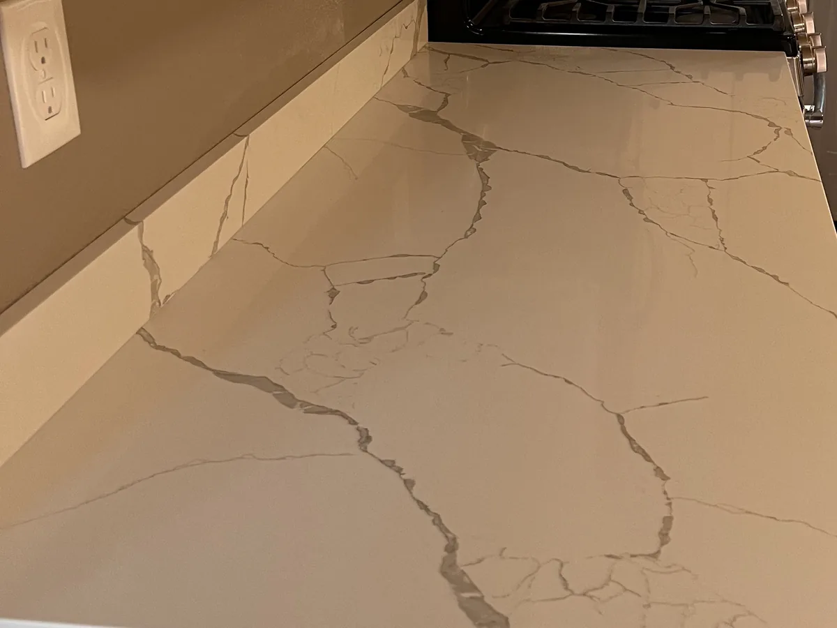 Quartz kitchen countertop run beside a range, with engineered grey veining spreading across the polished surface