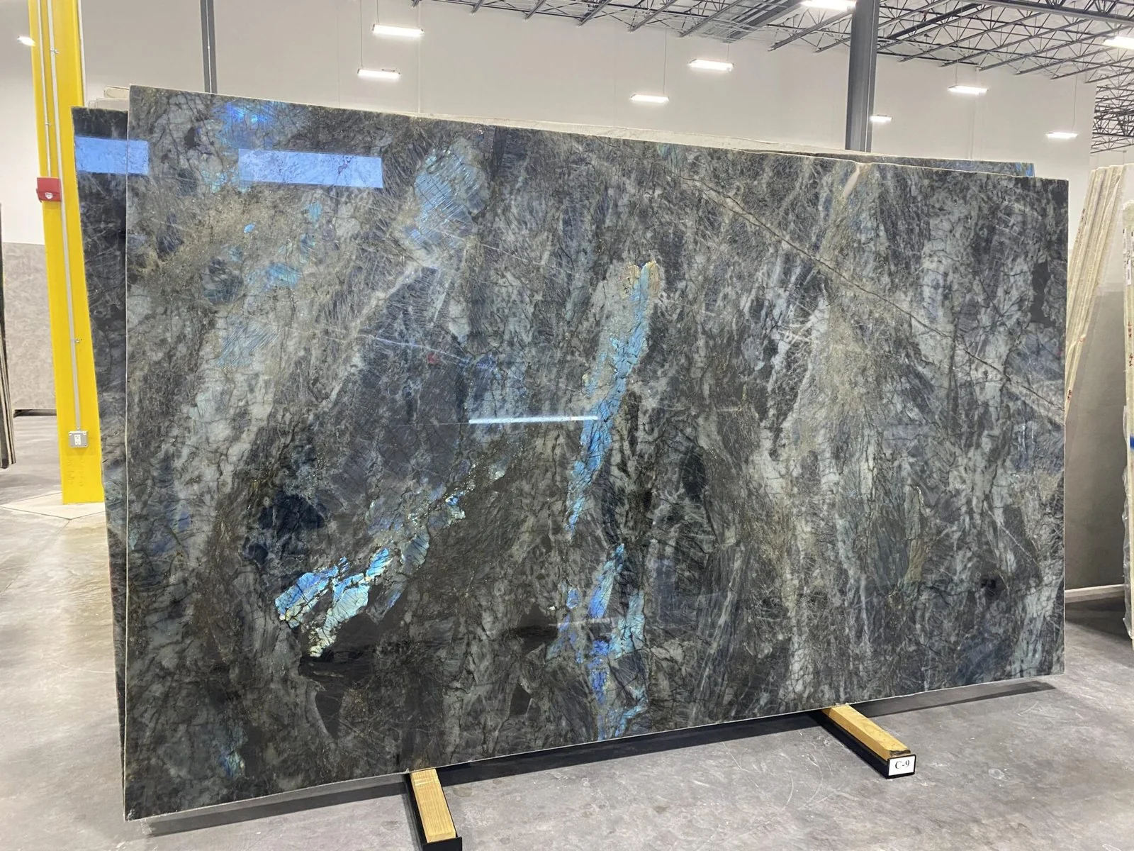 Large dark stone slab with blue mineral flashes displayed on supports