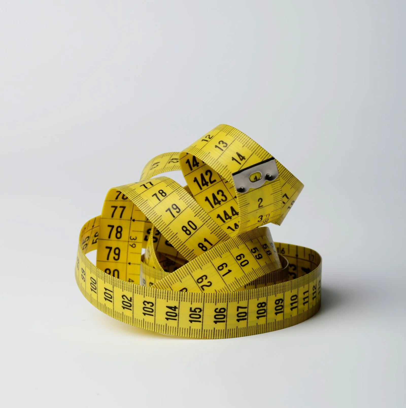 Yellow measuring tape loosely coiled on a white surface