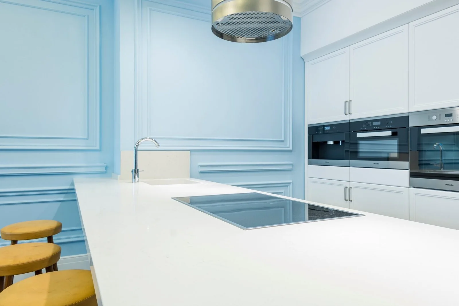 Bright kitchen with pale blue cabinetry and a white countertop around the sink
