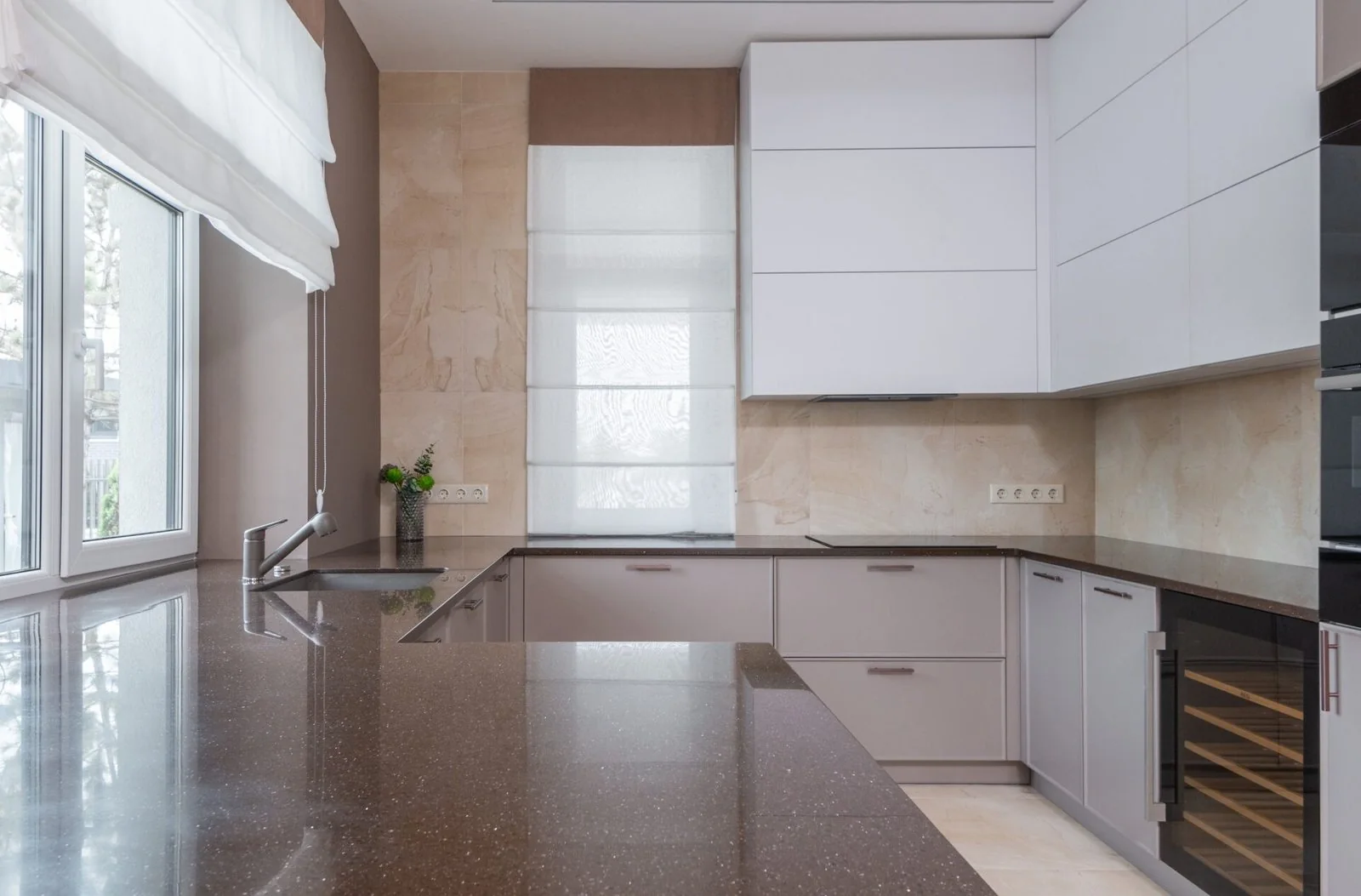 White kitchen with dark countertops and large windows