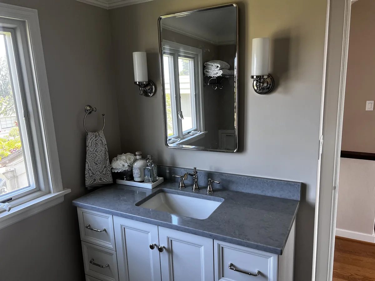 Bathroom vanity with a gray quartz countertop and a white undermount sink below a framed mirror