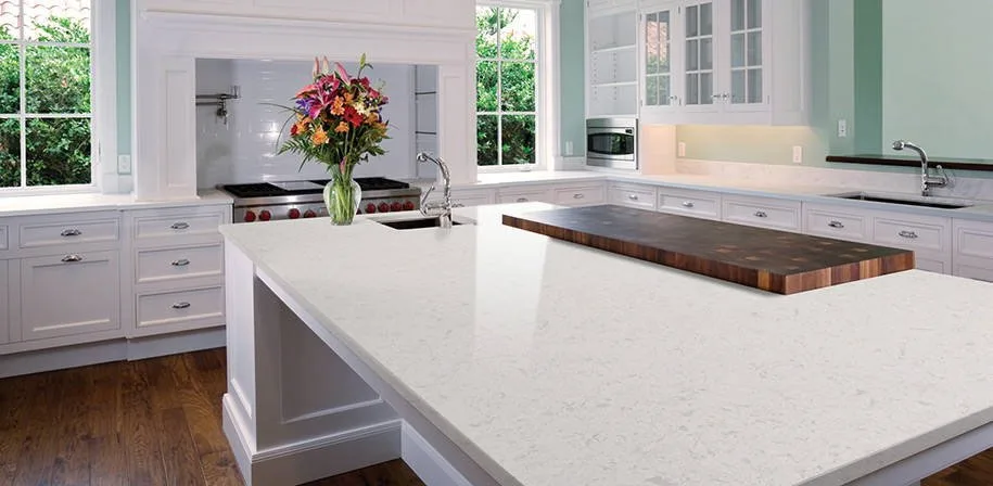 Bright kitchen with a pale island countertop, white cabinets, and windows