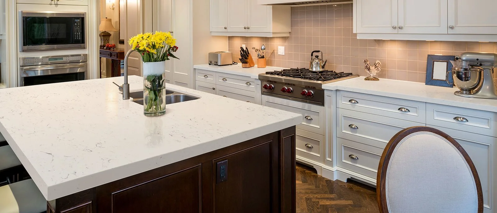 Light quartz island countertop with flowers, white cabinets, and a wood island base