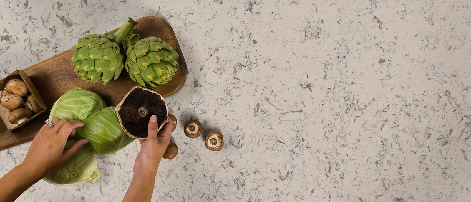 Overhead view of a white and gray patterned countertop with vegetables
