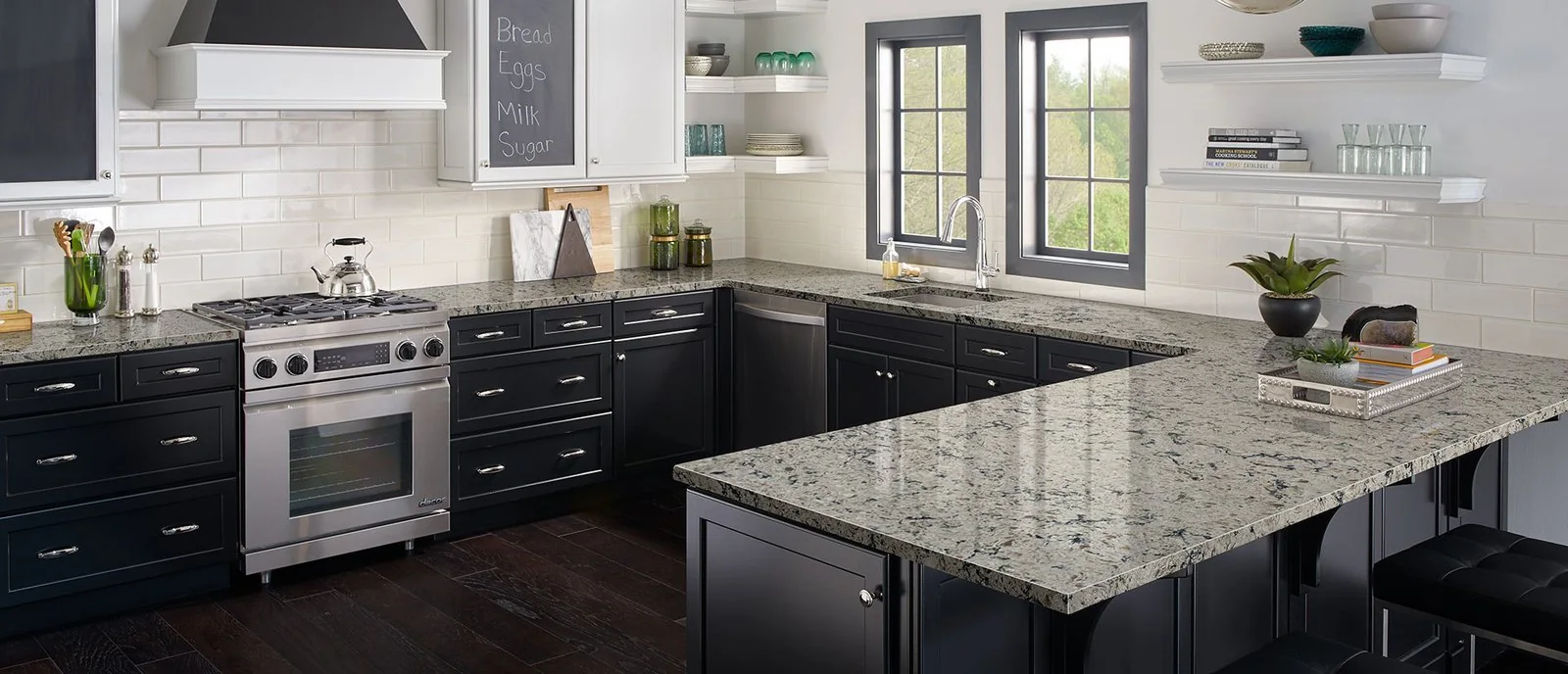 Kitchen with cream and gray patterned counters, dark base cabinets, and stainless steel appliances