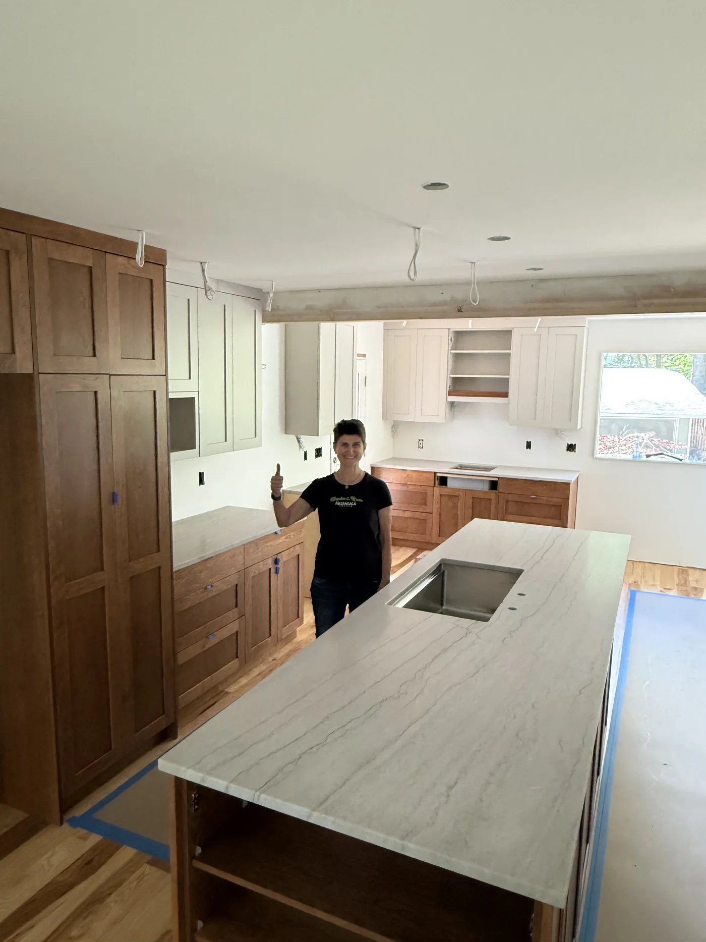 Homeowner giving a thumbs-up in front of her new kitchen island