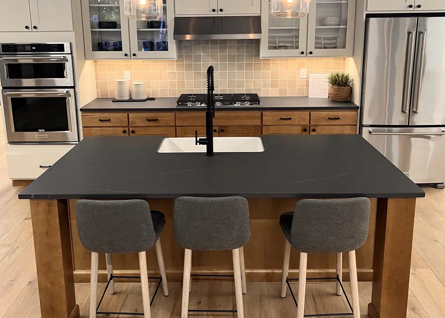 Dark island on a wood base, with stools. A Top Granite project