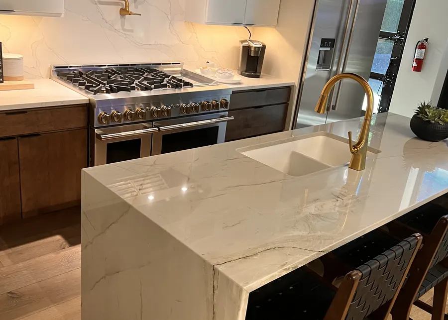 Marble island with a waterfall edge and gold faucet. A Top Granite project