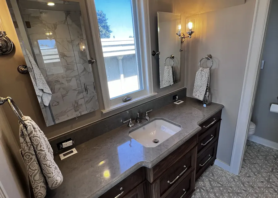 Dark double vanity with a chandelier. A Top Granite project