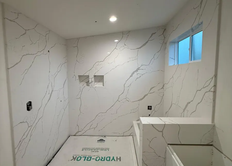 Full-height slab shower walls and vanities. A Top Granite project