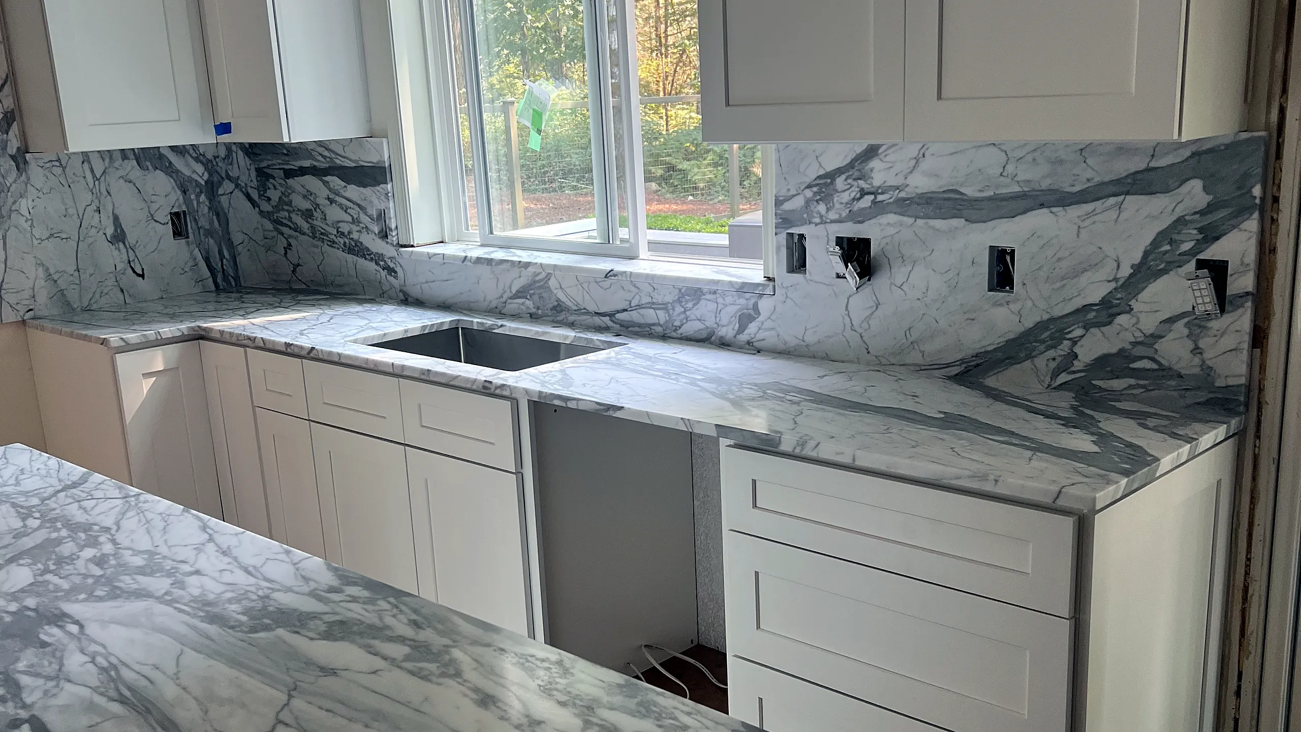 Marble countertop and full-height marble backsplash in a white kitchen by Top Granite