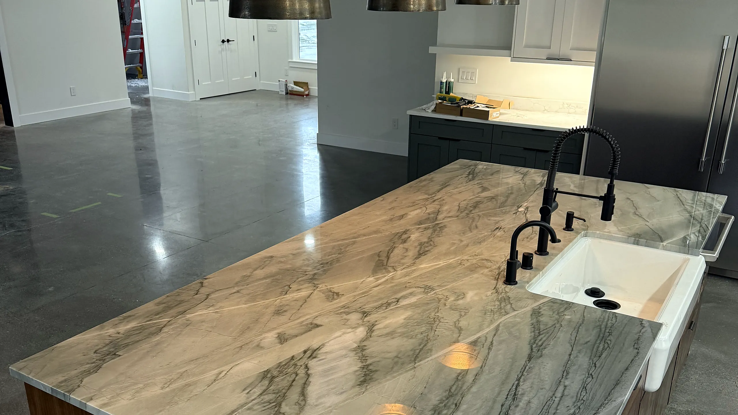 Quartzite island with a farmhouse sink and black faucet in a Top Granite kitchen project