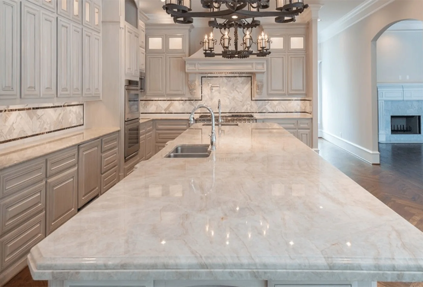 A luxury kitchen with a marble island and chandelier. A Top Granite project