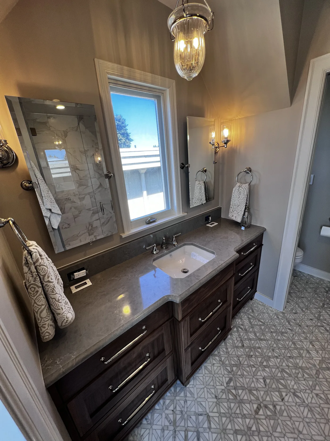 Dark double vanity with a chandelier. A Top Granite project