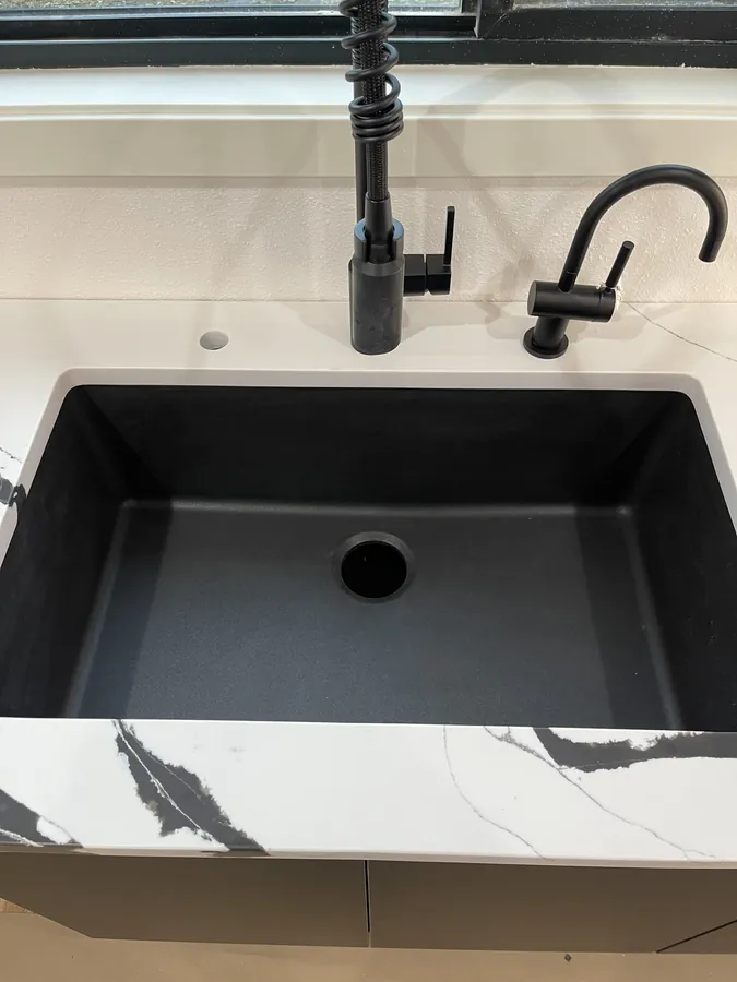 Black undermount sink with a light veined countertop, shown as a design detail