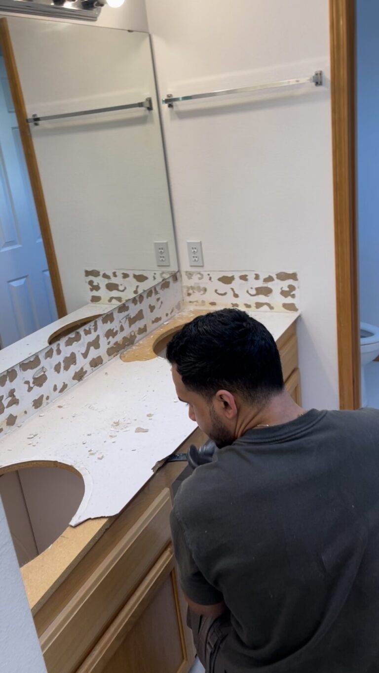 A man using tools to carefully demolish an old kitchen countertop in preparation for replacement