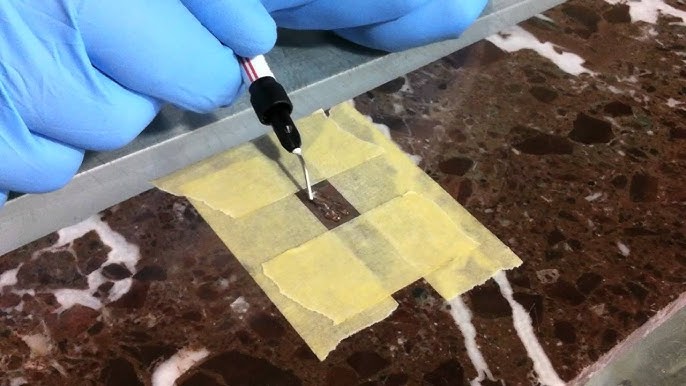 A close-up of a granite countertop chip being repaired